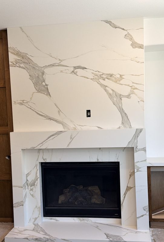 Floor-to-ceiling white porcelain slab fireplace surround with gray veining and a raised hearth