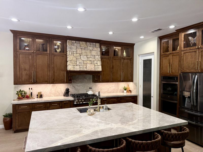 Kitchen with walnut cabinets, stone range hood and a large Taj Mahal quartzite island