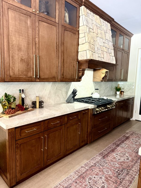Walnut kitchen cabinets with Taj Mahal quartzite counters and slab backsplash along the range wall