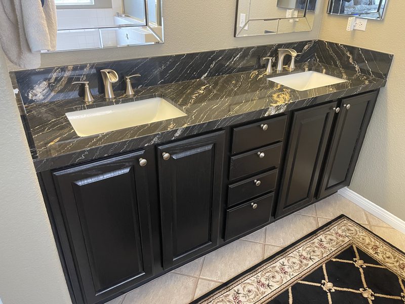 Double vanity with a black and gold granite top and dark cabinets